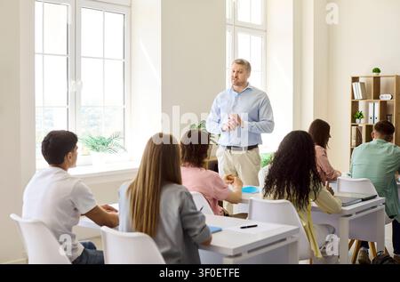 Professor leading discussion with students in classroom during college lesson Stock Photo
