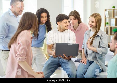Diverse students with teacher working on laptop project discussion in classroom Stock Photo