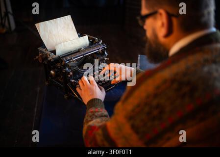 Over the shoulder view of a man typing on a typewriter Stock Photo