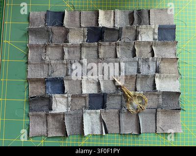 Close-up of the back of a handmade denim patchwork fabric woven from recycled jeans pieces, with a ornate vintage scissors Stock Photo