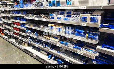 Iserlohn, Germany - June 20, 2026: Shelves in a hardware store are stocked with various paint cans, rollers, brushes, and painting supplies inside Act Stock Photo