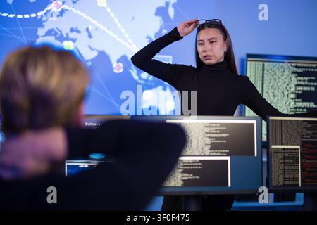 Cybersecurity professionals analyzing real-time threat data in a control room setting Stock Photo