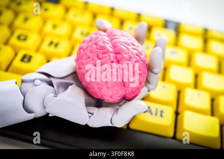 Robot hand holding a brain in front of a computer keyboard, symbolic photo artificial intelligence Stock Photo