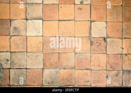 Terracotta floor features rustic square clay tiles. Weathered vintage texture displays warm orange brown tones. Antique ceramic surface with natural e Stock Photo