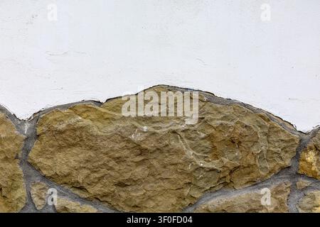 White Plaster Wall Above Rough Stone Masonry. White plaster wall meets rough stone masonry with gray mortar lines, exposed rock texture, and a clean Stock Photo