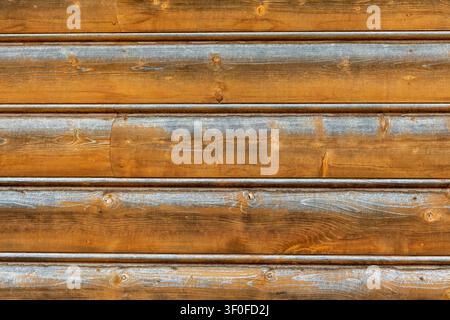 Weathered Wooden Plank Siding Texture. Horizontal wooden planks show warm brown grain, knots, gray weathered streaks, seams, and rustic siding texture Stock Photo