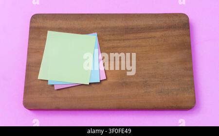 Pastel Sticky Notes on Wooden Board with Pink Background Stock Photo