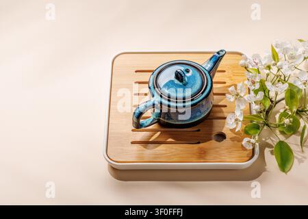 Blue ceramic teapot with blooming spring branch on wooden tray in minimal asian style composition Stock Photo
