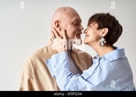 A joyful senior couple hugs tightly, showcasing their love and stylish outfits with smiles. Stock Photo