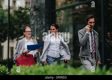 Business colleagues walking and talking outside a modern office building during a daytime commute Stock Photo