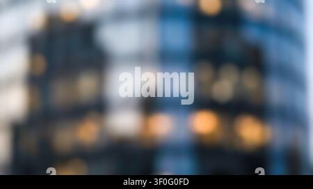 Defocused contemporary corporate business office exterior displays glowing warm illuminated windows against dark architectural glass, soft abstract bo Stock Photo