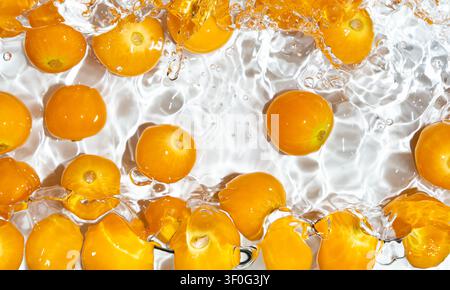 Physalis fruits splashing in water with bubbles top view Stock Photo