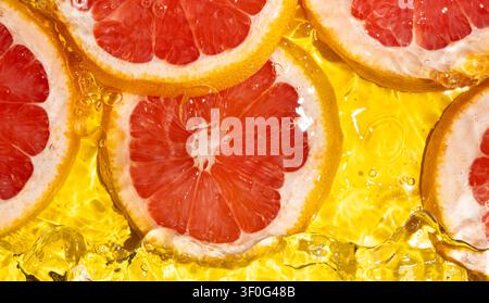 Macro texture of pink grapefruit slices in liquid with bubbles and waves Stock Photo