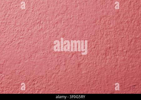 Horizontal close up macro shot of a dusty pink painted concrete wall surface with rough uneven plaster stucco texture layer for colorful home backdrop Stock Photo