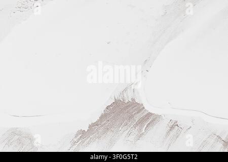 Horizontal macro top down shot of white texture paste brushstrokes applied to a brown primed artist canvas creating a minimalist abstract pattern on s Stock Photo