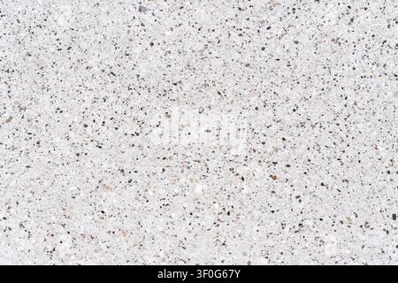 Macro close up of a polished white quartz surface with small grey, black and brown mineral fragments. Abstract terrazzo stone texture background Stock Photo