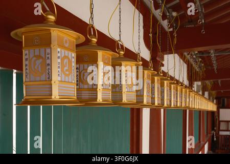 A long row of traditional ornate hanging gold metal lanterns at Shitenno-ji Temple, Osaka, Japan. Stock Photo