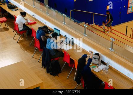 High-angle view of people and students using laptops and reading in the Library of Birmingham, UK Stock Photo