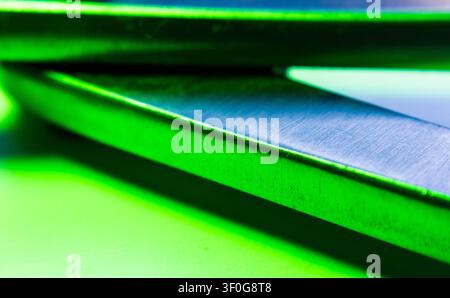 Angular metal surfaces meeting at folded edge glowing green under contrasting light Stock Photo