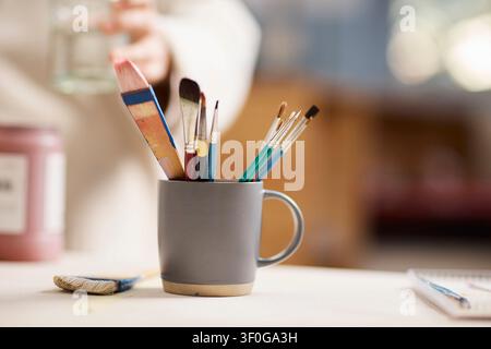 Pottery Studio Paintbrushes in Mug on Worktable With Creative Artist and Small Business Vibe Stock Photo