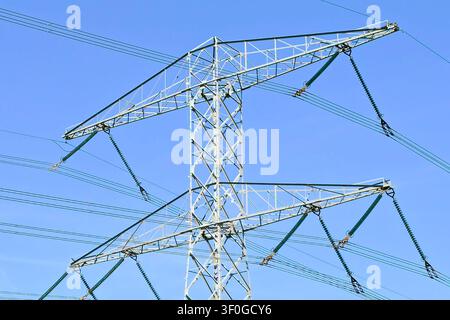 High voltage transmission tower and power lines against clear blue sky Stock Photo