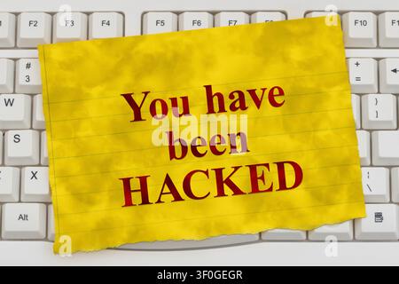 You have been Hacked text on a yellow line paper on a white computer keyboard for cybersecurity and ransomware Stock Photo