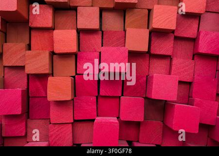 A textured pattern formed by small, square-ended timber blocks, showing variations in protrusion and gradient tones from soft coral orange to deep mag Stock Photo
