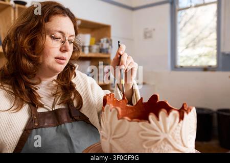 Pottery Artist Working in Small Business Studio Painting a Glazed Ceramic Vase With Care Stock Photo