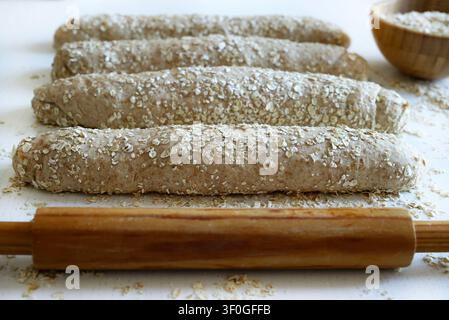 Homemade whole wheat oat bread on a floured surface with rolling pin.  Healthy baking and organic food. Traditional bakery and bread making. Stock Photo