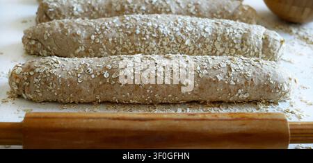 Homemade whole wheat oat bread on a floured surface with rolling pin.  Healthy baking and organic food. Traditional bakery and bread making. Stock Photo
