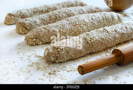 Homemade whole wheat oat bread on a floured surface with rolling pin.  Healthy baking and organic food. Traditional bakery and bread making. Stock Photo