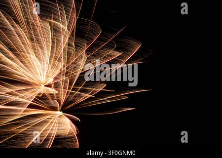 A bright golden firework exploding from the left edge of the frame, showing expanding long-exposure light trails against a dark night sky. Stock Photo