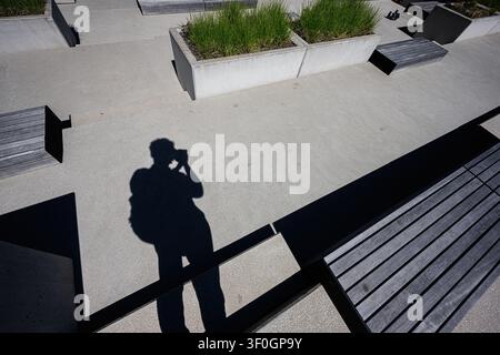 Silhouette of a photographer taking a photo on a modern concrete plaza in Katowice, Poland Stock Photo