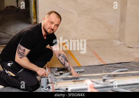 Construction worker cutting ceramic tile using tile cutter while working on bathroom renovation Stock Photo