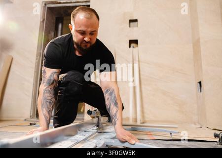 Construction worker cutting ceramic tile using manual tile cutter while working on bathroom renovation Stock Photo