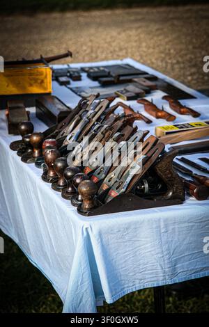 White cloth covered table with a selection of traditional carpentry tools with copy space including a line of hand held wood planes Stock Photo