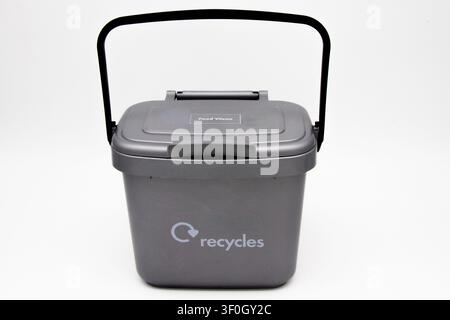 Small grey indoor plastic caddy with lockable lid against a white background for domestic food waste that is collected and recycled Stock Photo