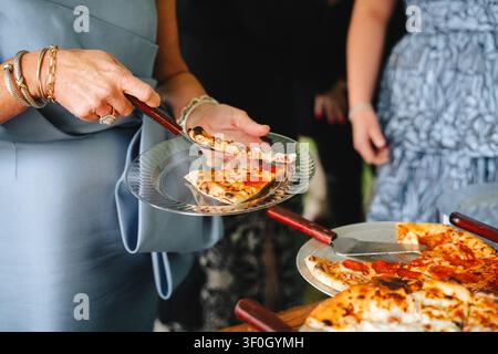 Woman serving pizza at an outdoor event or wedding reception Stock Photo