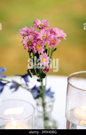 Pink daisy bouquet with candles on table Stock Photo