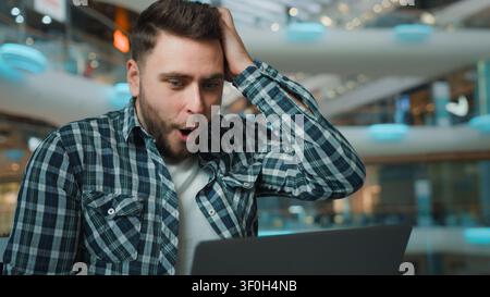 Caucasian male winner amazed hispanic man businessman freelancer employee work distant with laptop use internet network win online bet business Stock Photo