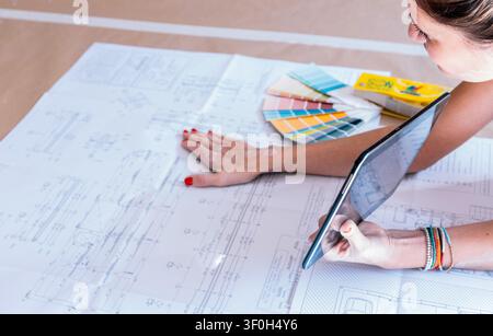 Young woman designing architectural blueprint using a digital tablet for new home construction Stock Photo