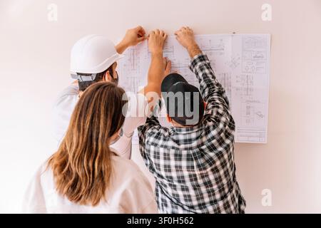 Professionals collaborating on architectural plans, discussing details during building renovation Stock Photo