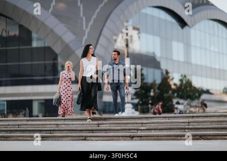Three professionals walking down city steps in front of a modern glass building Stock Photo