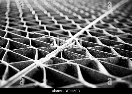 Monochrome close-up industrial steel floor grating showing repeating geometric pattern. Diminished perspective, shallow depth of field highlight textu Stock Photo