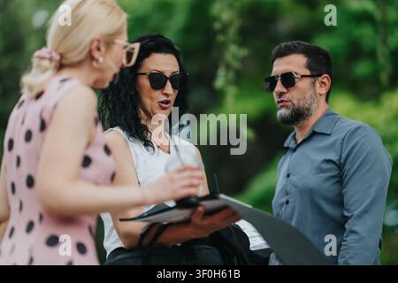 Three colleagues having an outdoor business meeting and discussion while reviewing documents Stock Photo