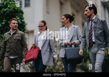 Four business professionals walking together on a city street between office buildings Stock Photo