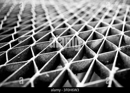 Monochrome close-up industrial steel floor grating showing repeating geometric pattern. Diminished perspective, shallow depth of field highlight textu Stock Photo