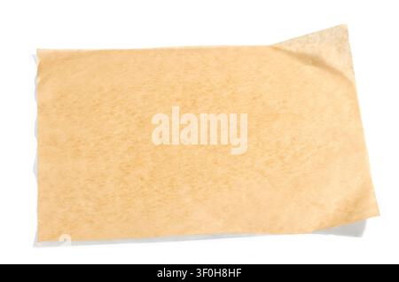 Overhead studio shot of a blank sheet of brown baking parchment paper, cleanly isolated on a pure white background with a soft natural shadow. The she Stock Photo