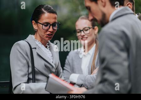 Business colleagues discussing notes during an outdoor meeting in professional attire Stock Photo