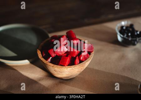Diced roasted beets in small wooden bowl on rustic table Stock Photo
